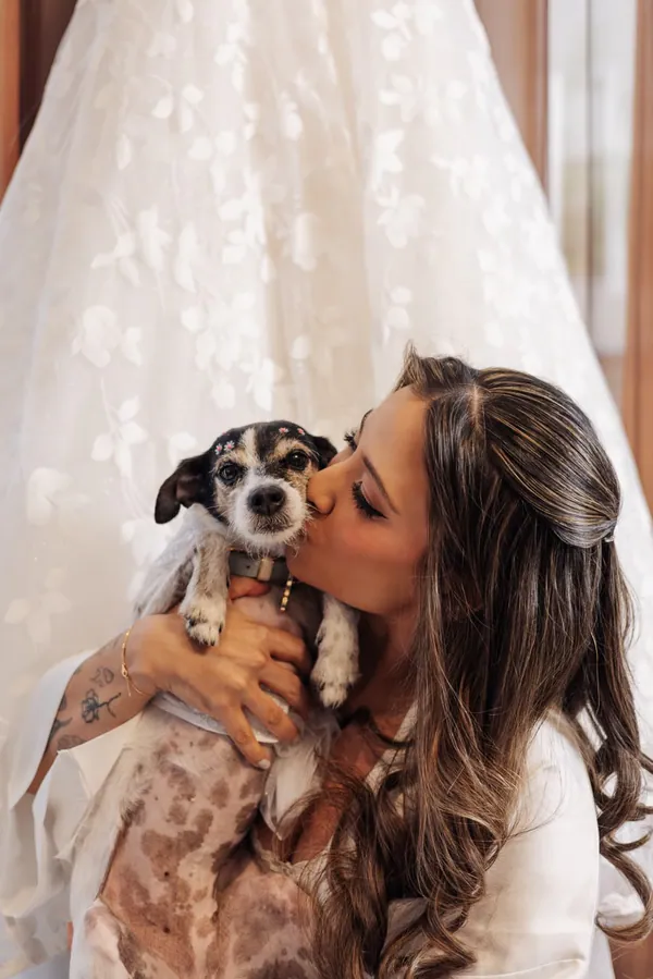 No making of, a noiva beija o cachorrinho, com o vestido pendurado atrás